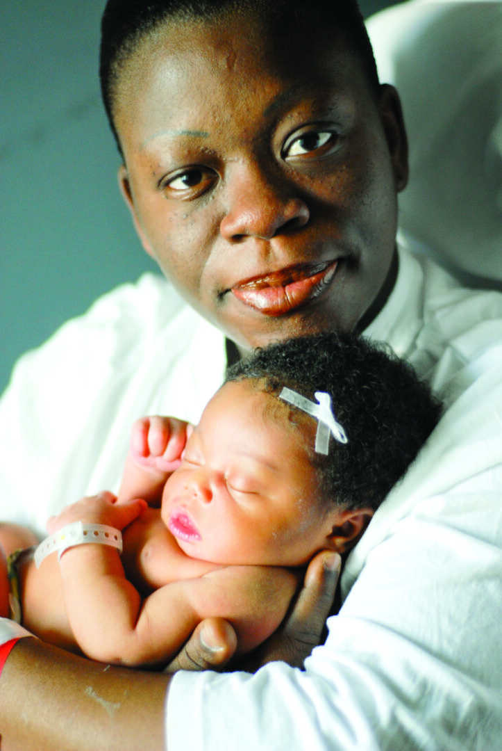 Parent cuddling infant with bow