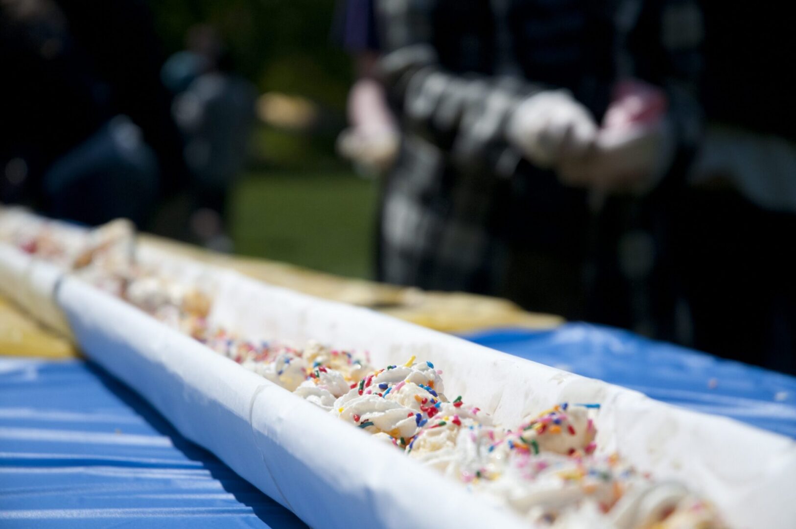 People serving a large ice cream dessert