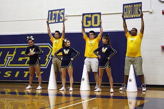 Cheerleaders holding motivational signs in gym