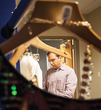 Man behind clothes hangers in fitting room