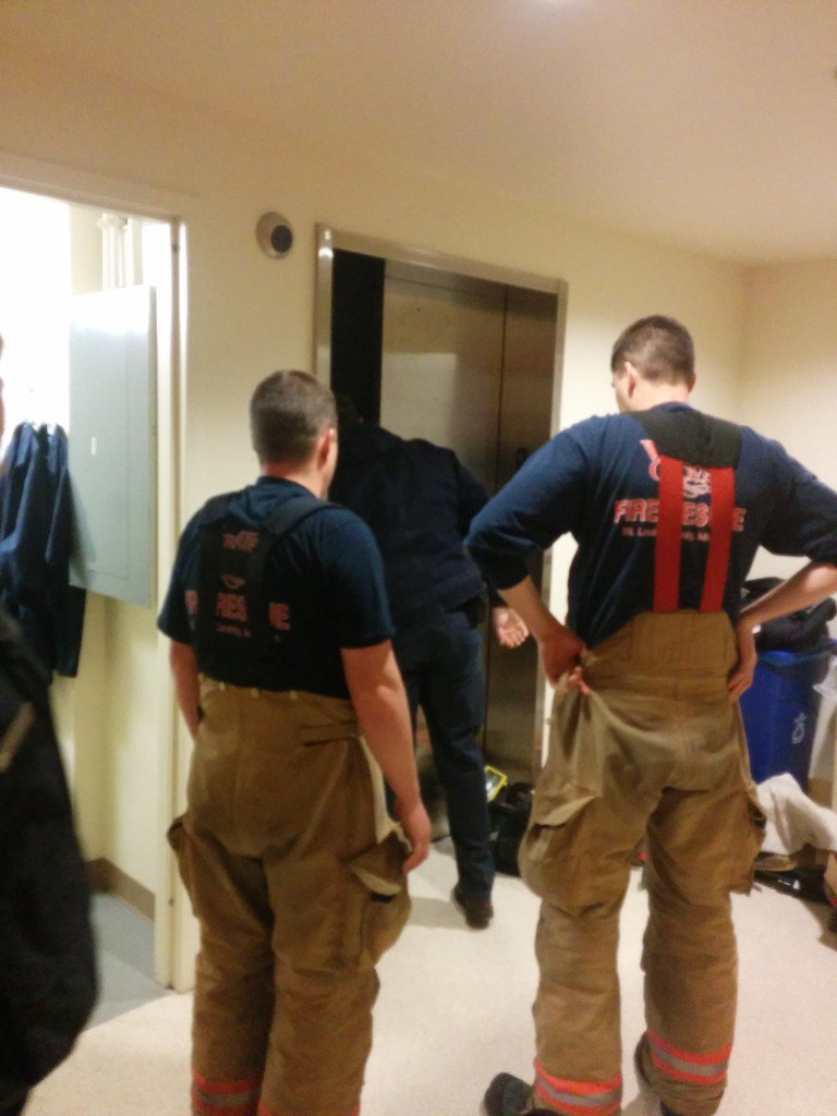 Webster Groves Firefighters and a Kone Elevator employee work to open an elevator that got stuck between two floors with two students inside. PHOTO BY LIVIE HALL