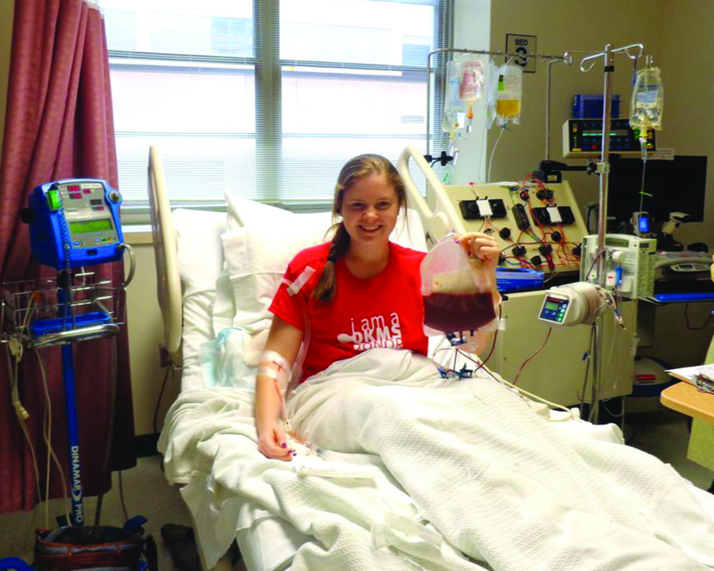 Freshman Erin Rasmussen smiles as she holds a bag of her own blood, which she donated to save a man who was diagnosed with leukemia.