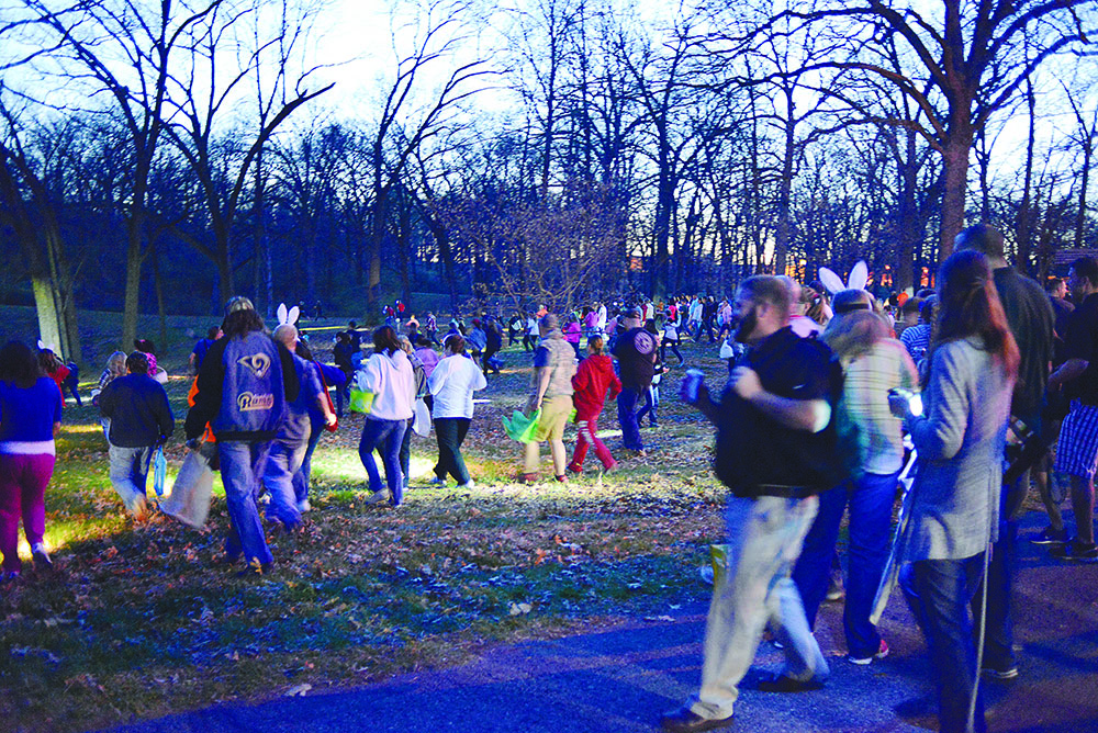 Crowd walking through a park at dusk