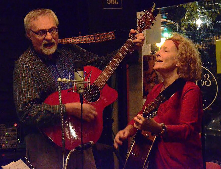 Duo performing with guitars on stage