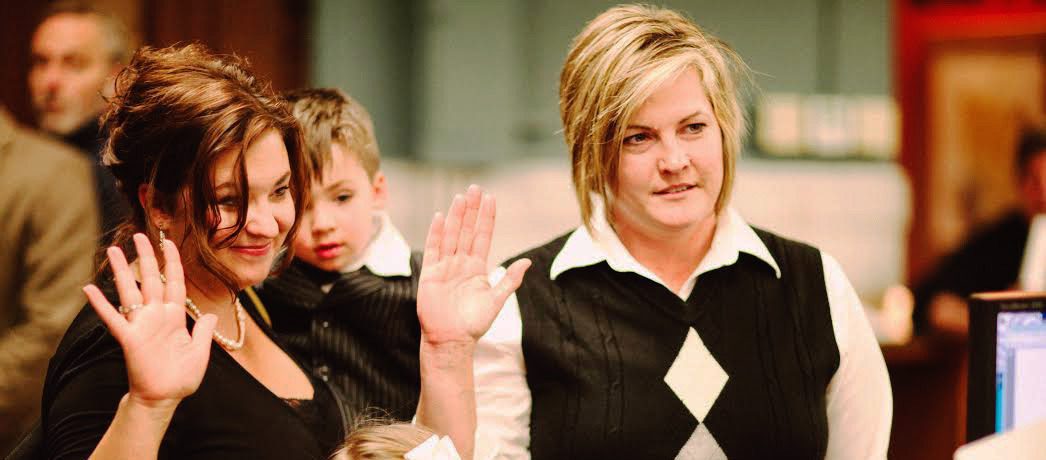 Women raising hands in a formal setting.