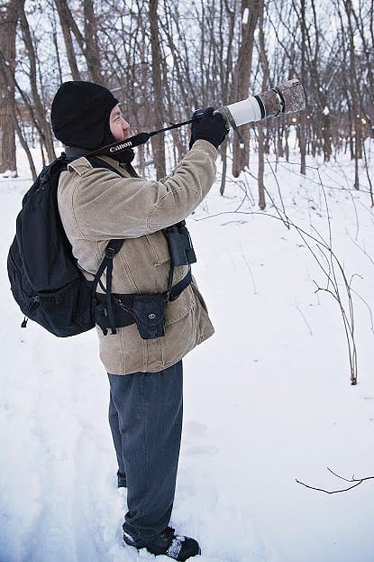 Photographer in snowy forest with camera