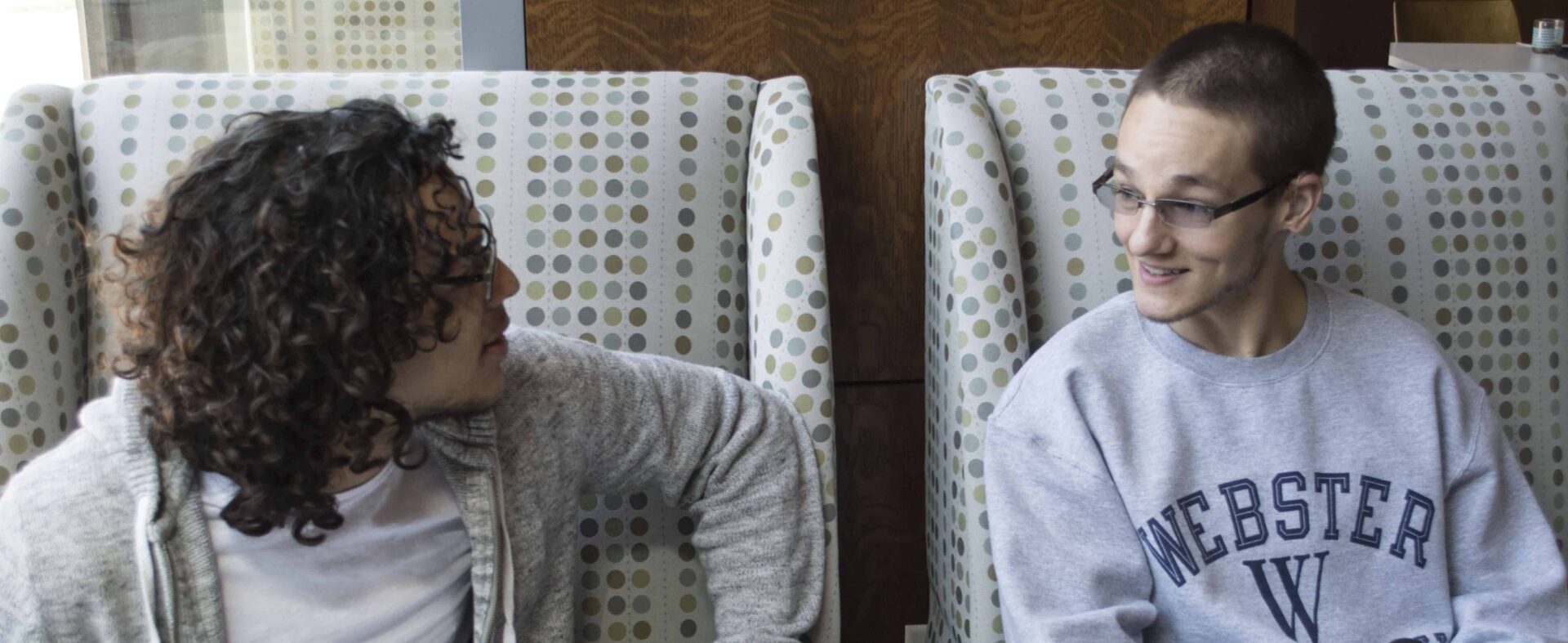 Two people chatting on patterned chairs.