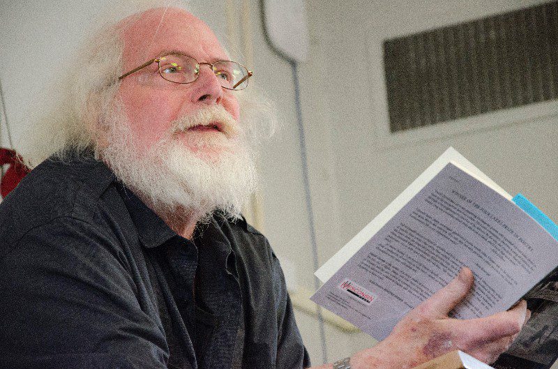 Elderly man reading a book aloud