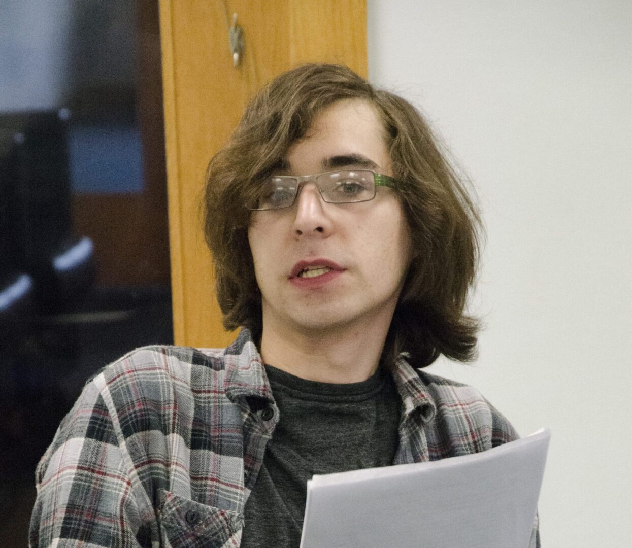Individual with glasses, long hair, reading