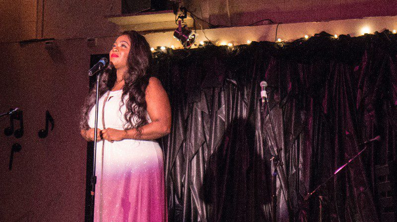 Woman in pink dress singing on stage