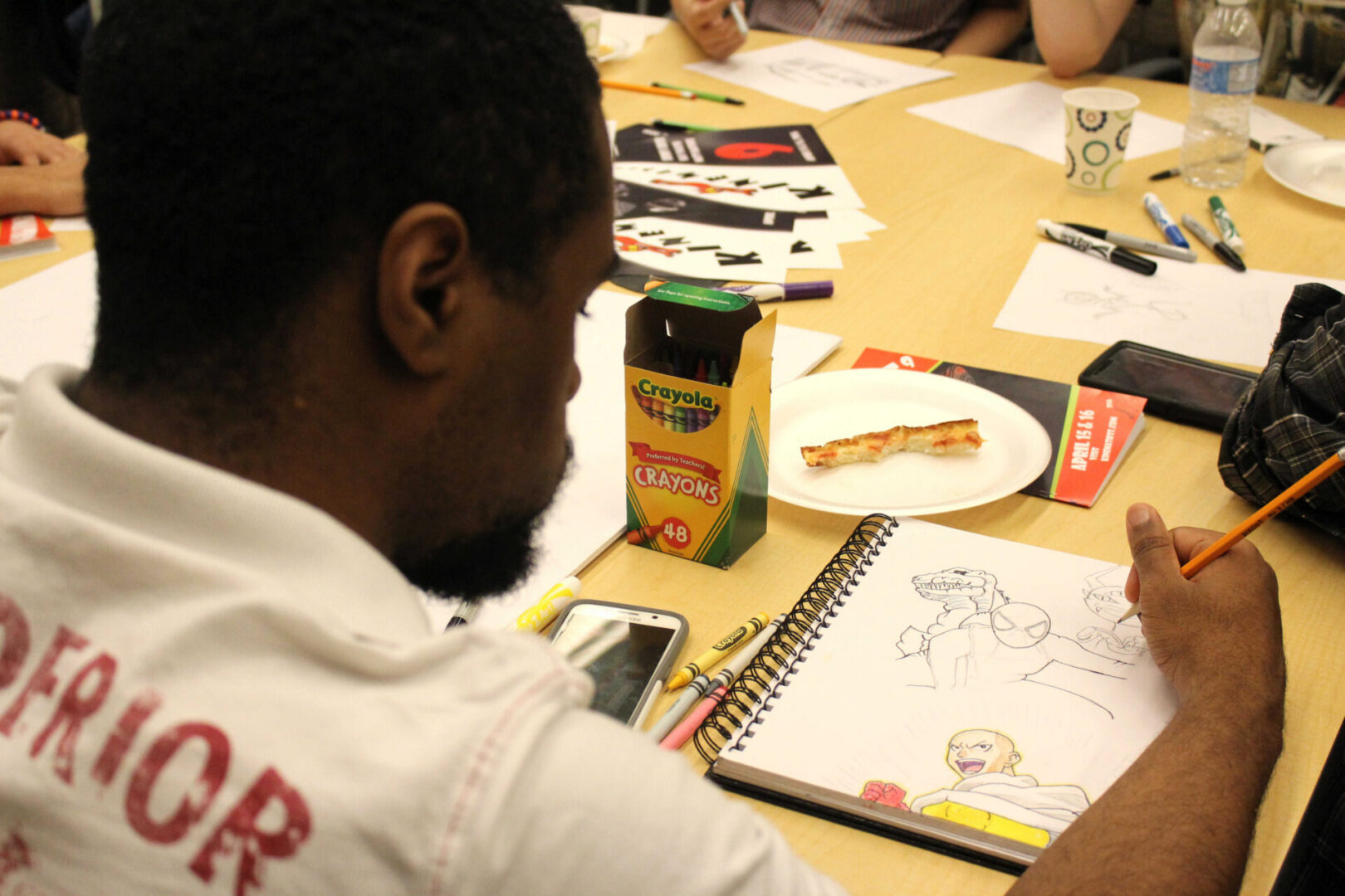 Artist focused on sketching with crayons nearby