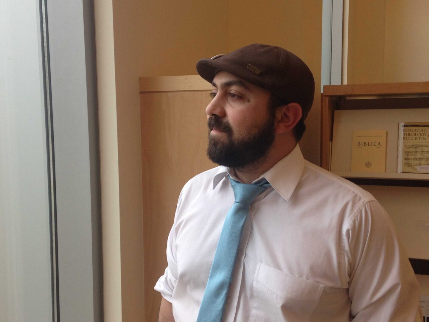 Bearded man in tie near bookshelves