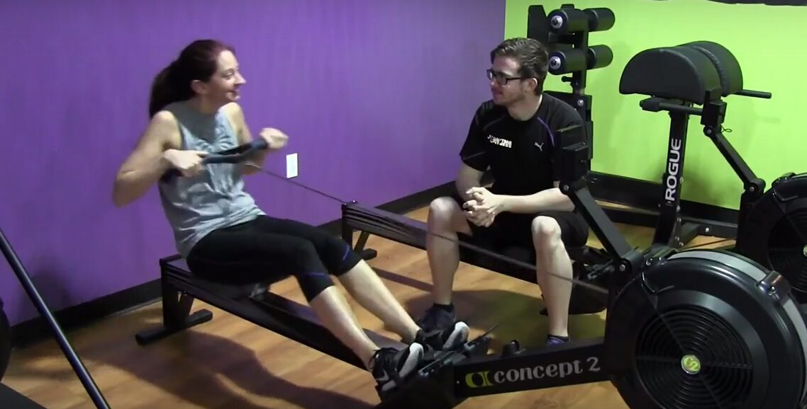 Personal trainer supervising rowing workout