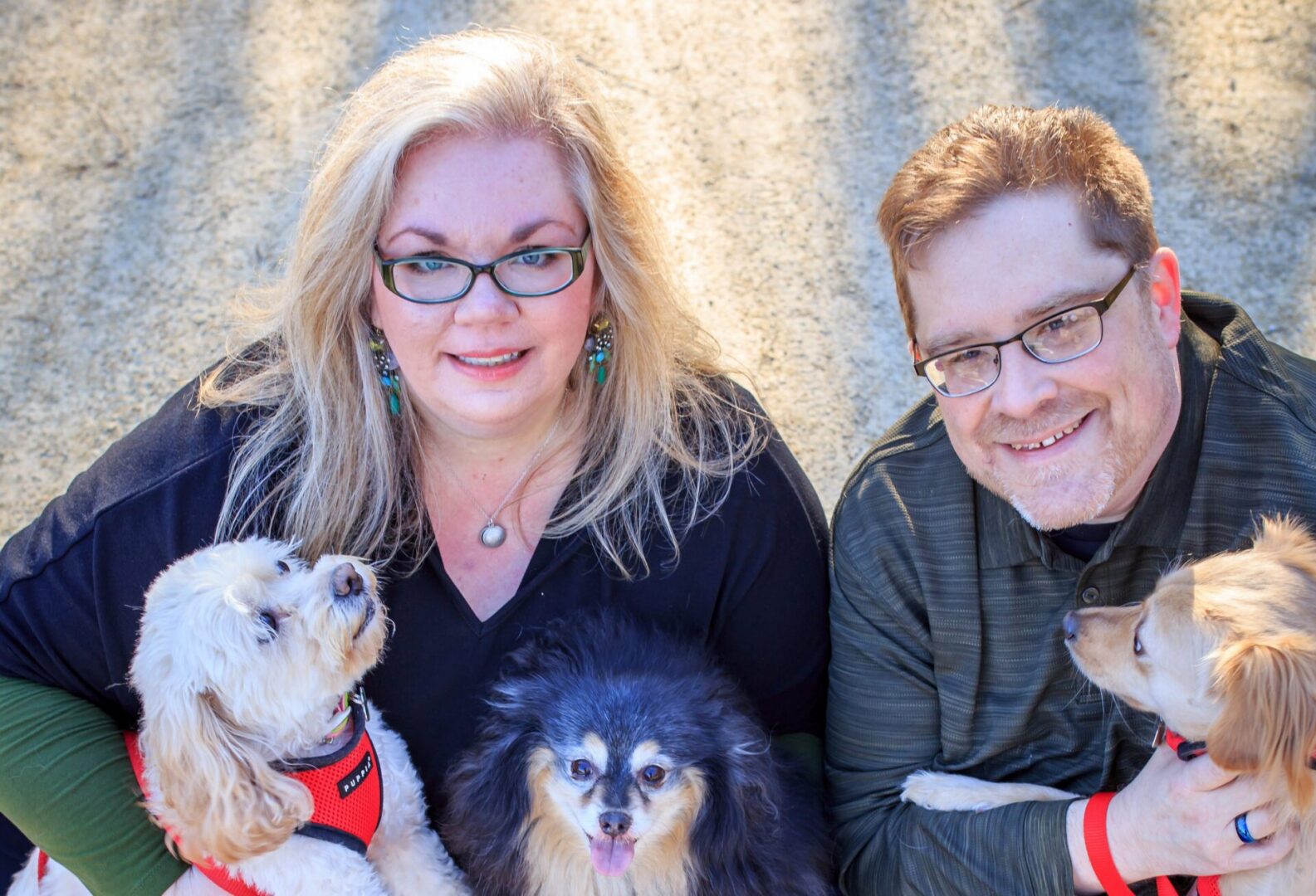 Two people and their three dogs outdoors