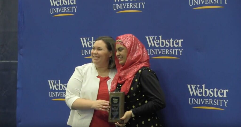 Two people posing with an award