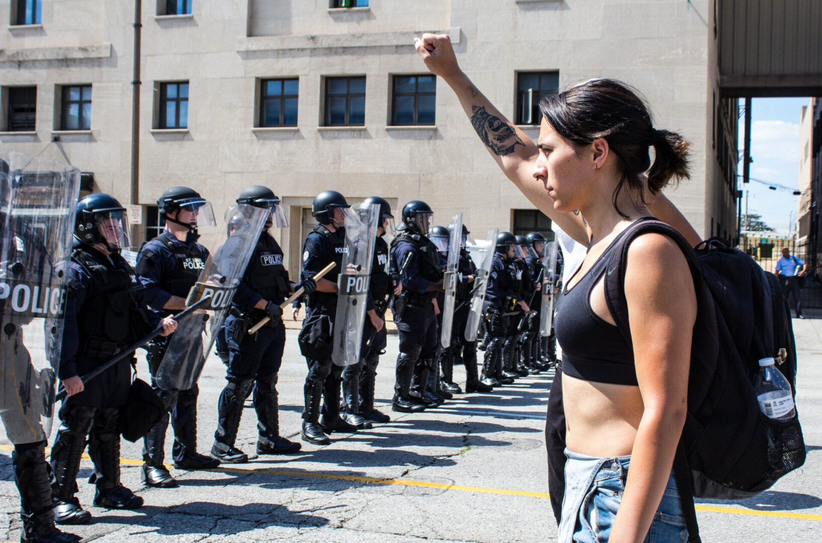 Protester raising fist facing police line