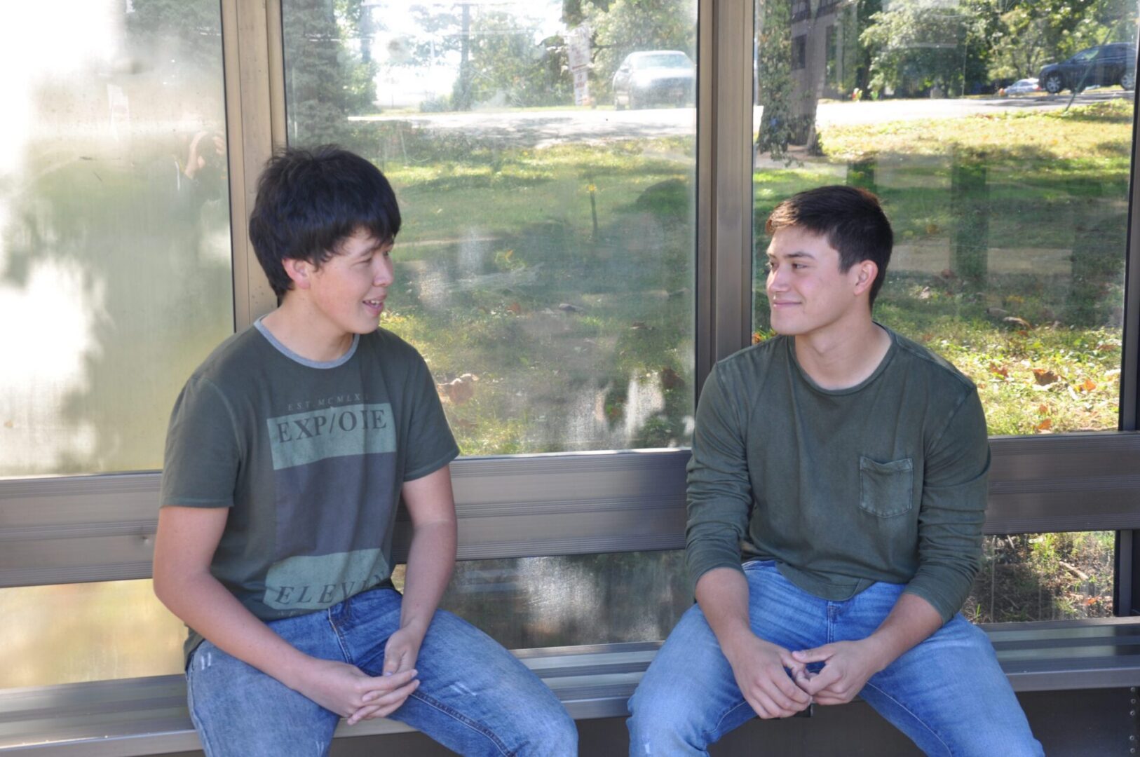 Two people talking by a window.