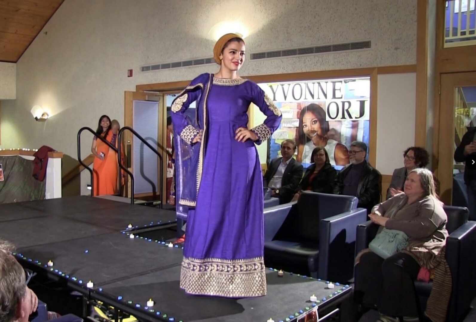 Woman modeling elegant purple attire on stage.