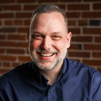 Smiling man in front of brick wall