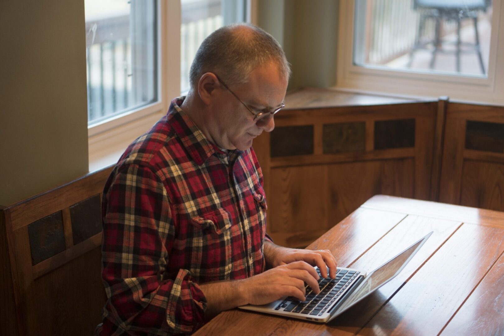 Individual in plaid shirt using laptop.