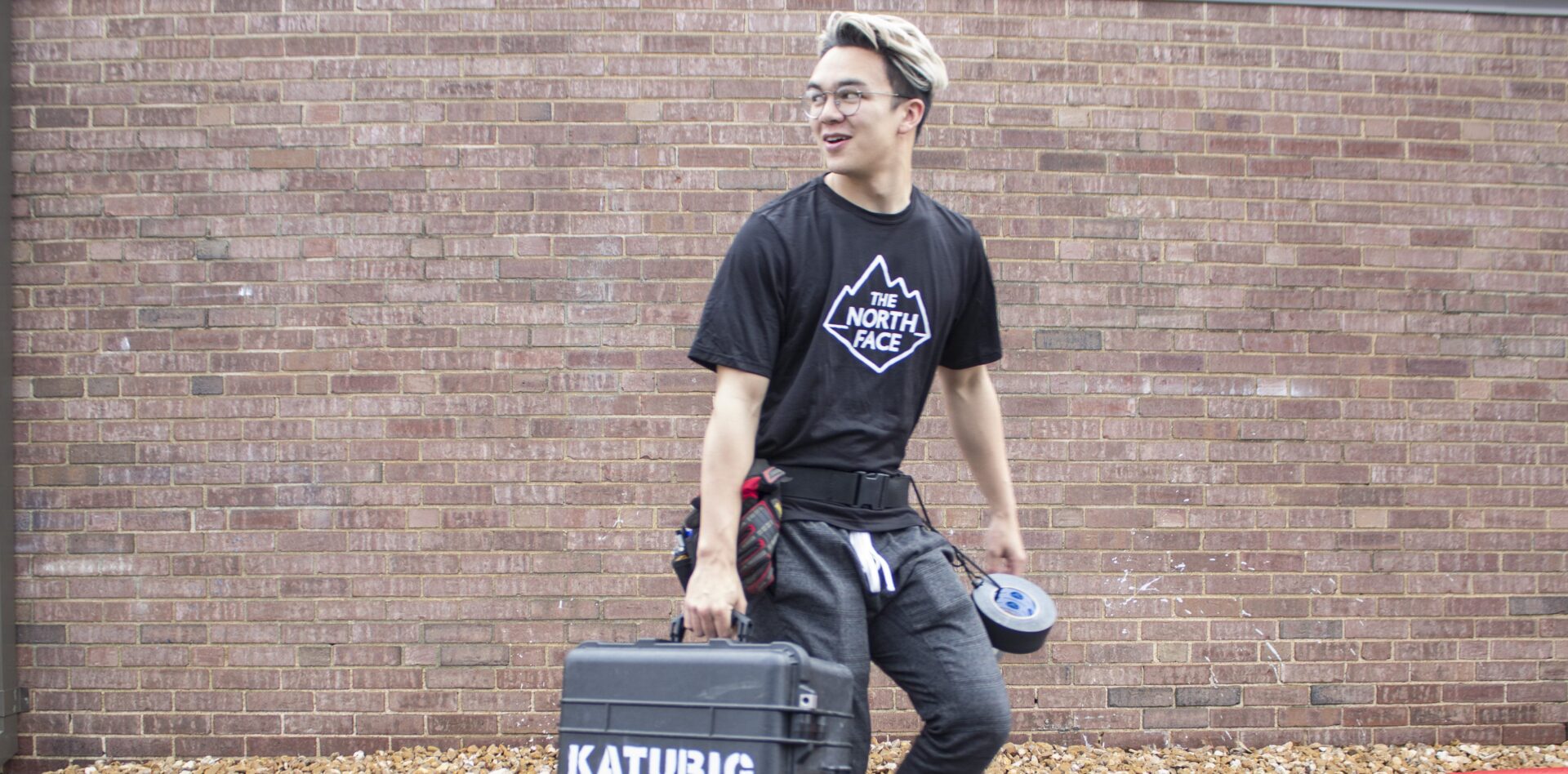 Person carrying tools against brick wall