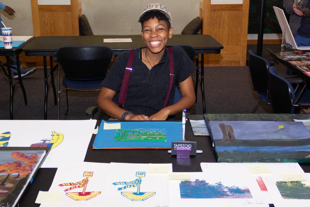 Artist smiling at art display table