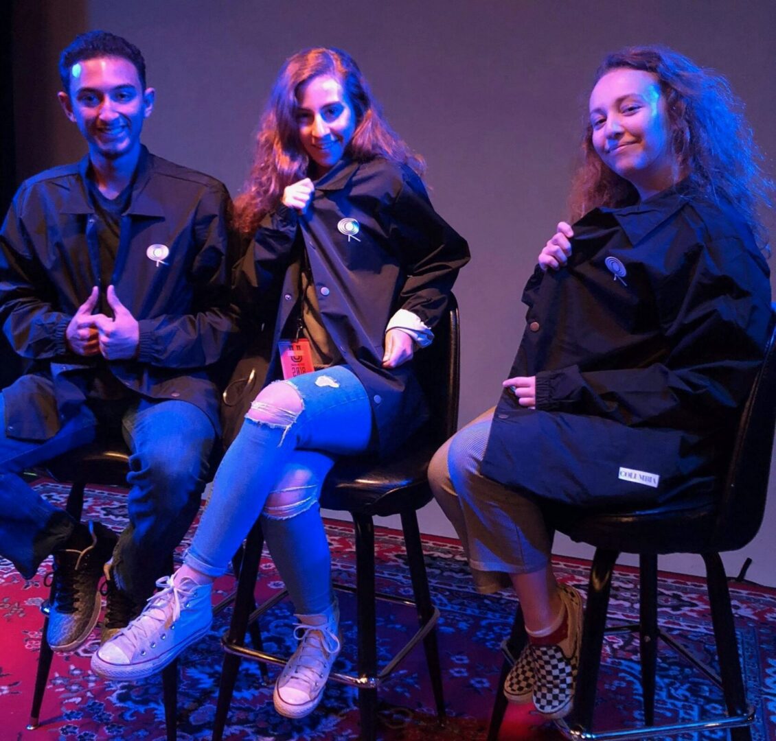 Friends posing in casual outfits on stage.