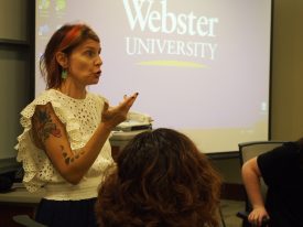 Instructor speaking before Webster University projected logo