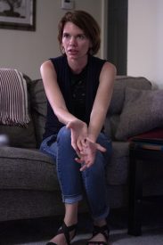 Woman sitting on couch with clasped hands