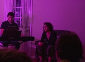 People performing music in purple-lit room