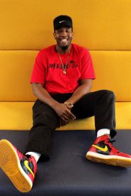 Man smiling in red shirt and sneakers