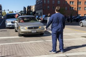 Person standing in city street before stopped car
