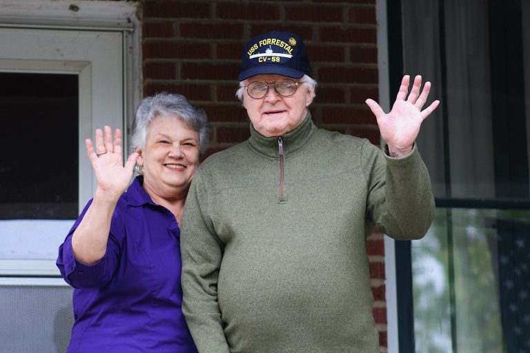 Elderly couple waving from porch