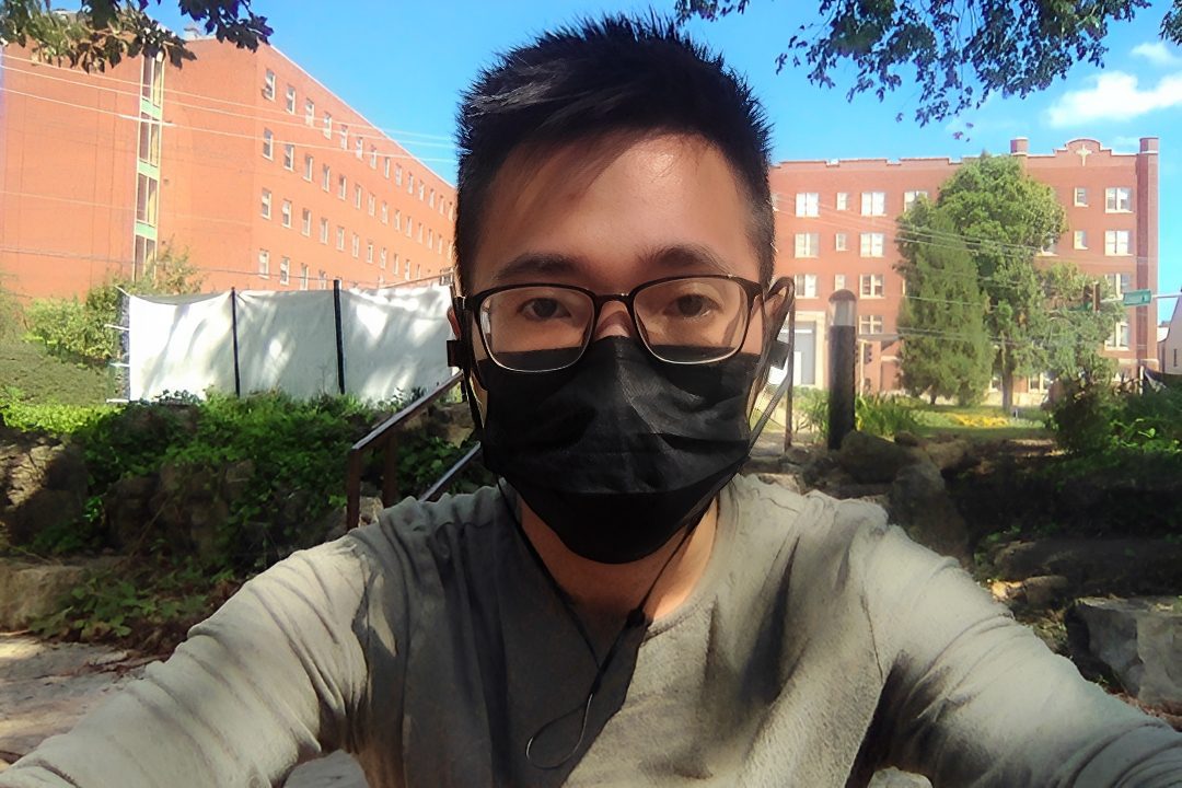 Masked person sitting outside in daylight