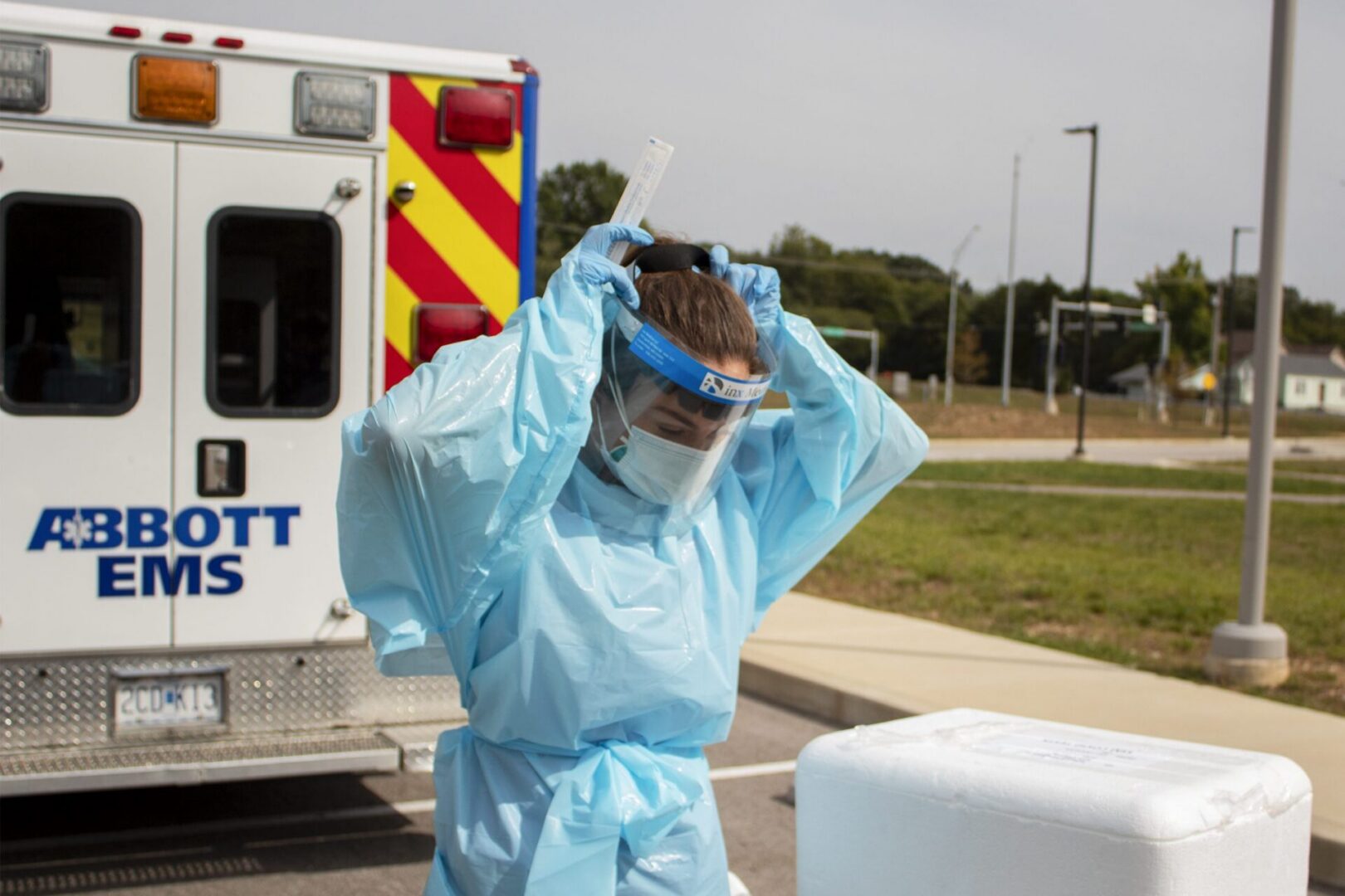 Medical professional adjusts face shield near ambulance