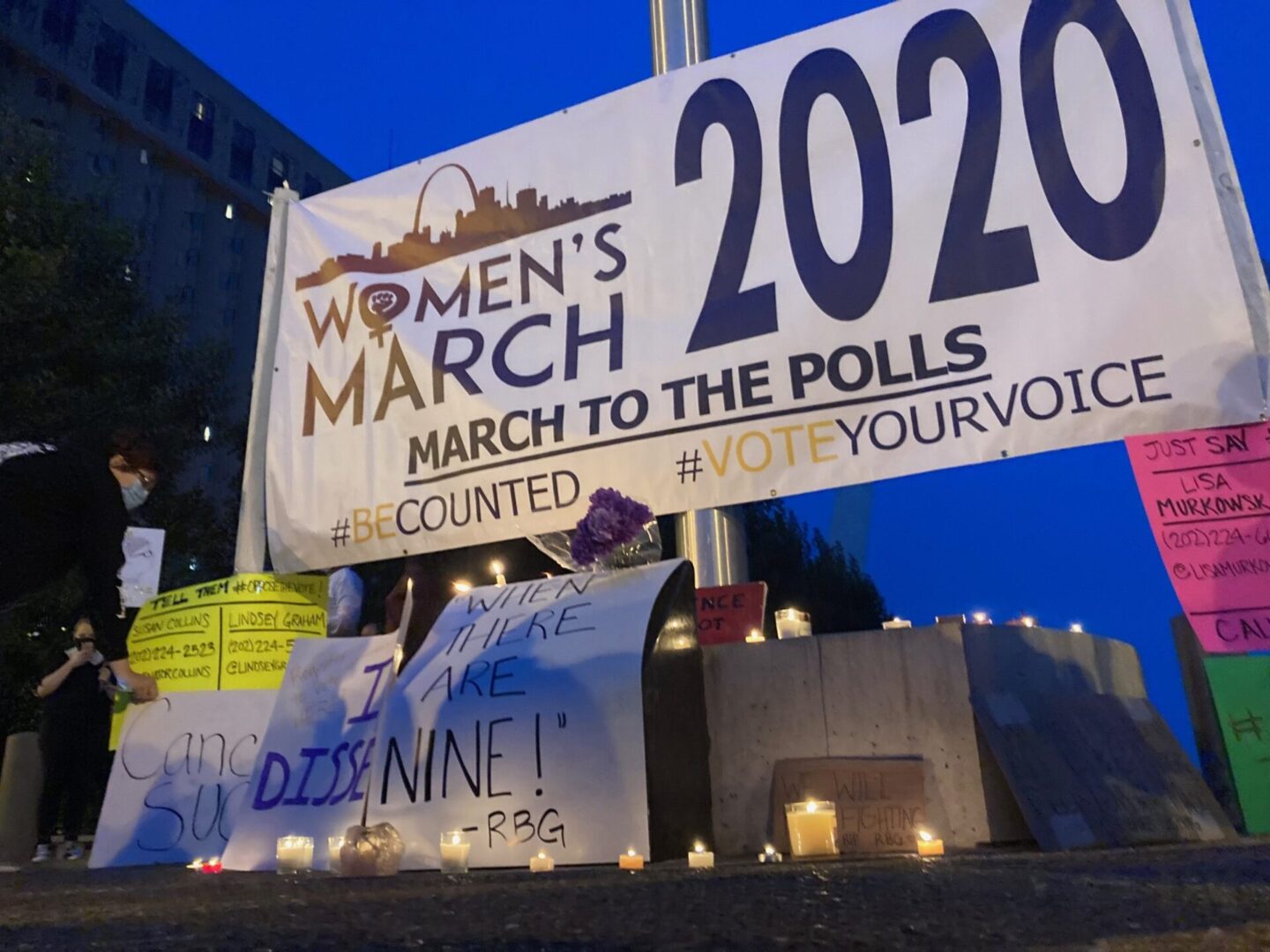 Protest signs and lit candles at rally