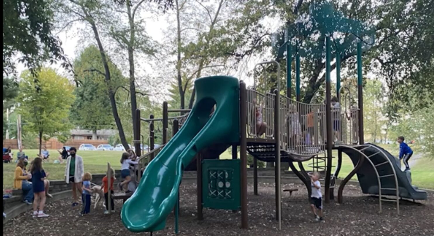 Children playing on a green playground structure.
