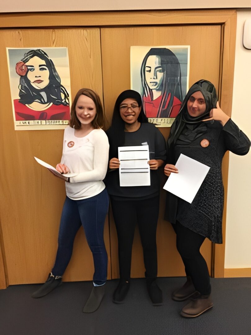 Three women posing with posters