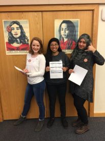 Women posing with papers and posters.