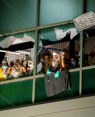 Protesters behind broken window with sign