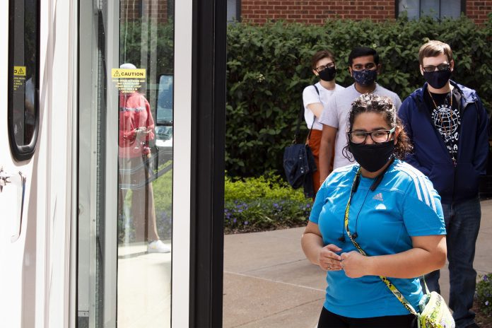 People wearing masks waiting for a bus