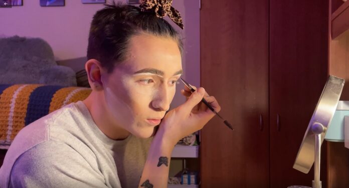 Individual using makeup brush near mirror
