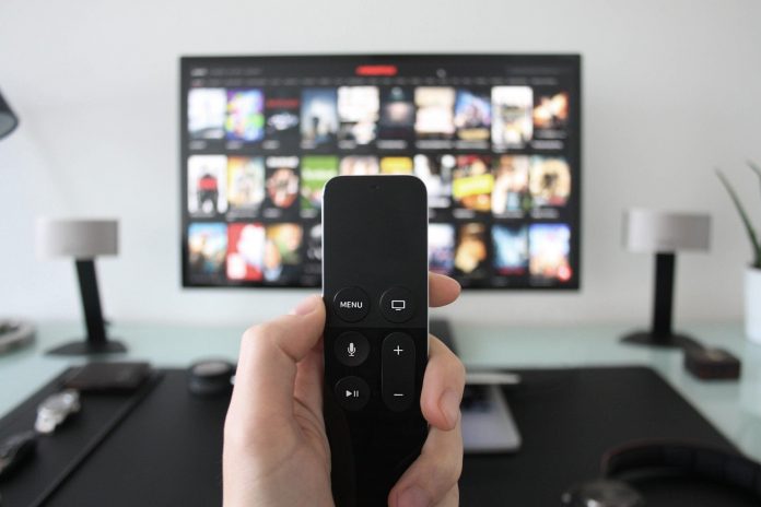 Hand holding remote towards a TV screen