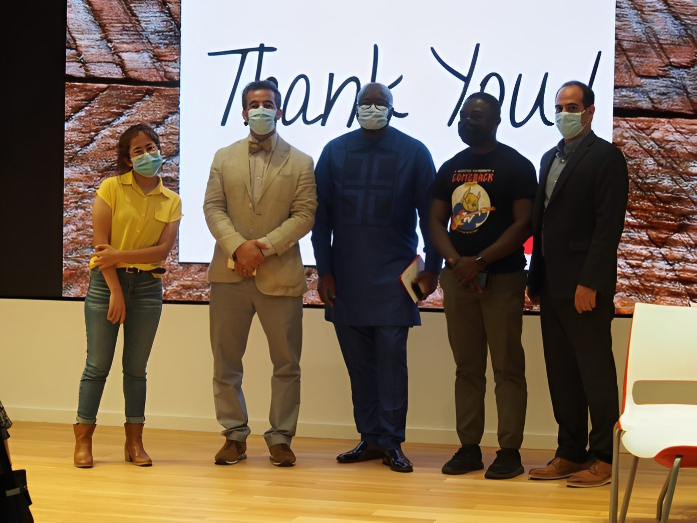 Team standing together, smiling behind masks