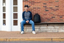 Man sitting on bench with backpack