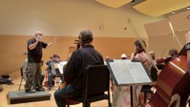 Conductor leading orchestra rehearsal in concert hall