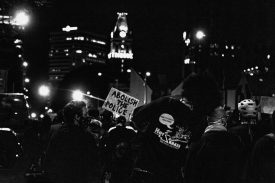Nighttime protest crowd with city skyline