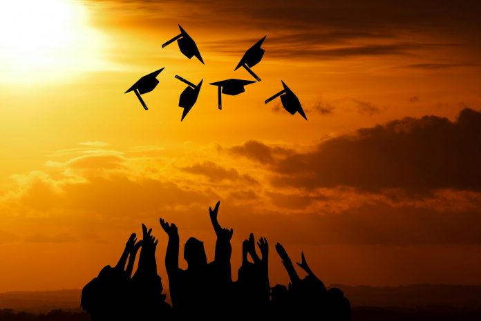 Graduates throwing caps in sunset sky