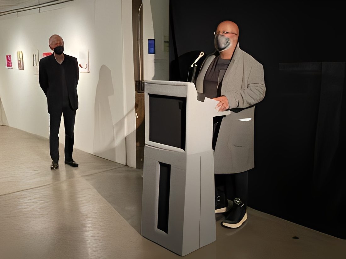 Man speaking at podium with mask
