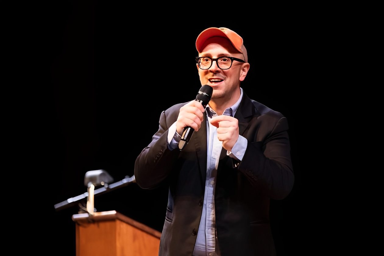 Man speaking on stage with microphone
